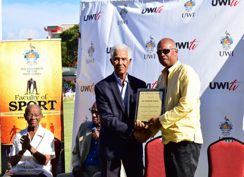 Professor Sir Hilary Beckles presents Sir Garfield Sobers with a Tribute plaque from The UWI